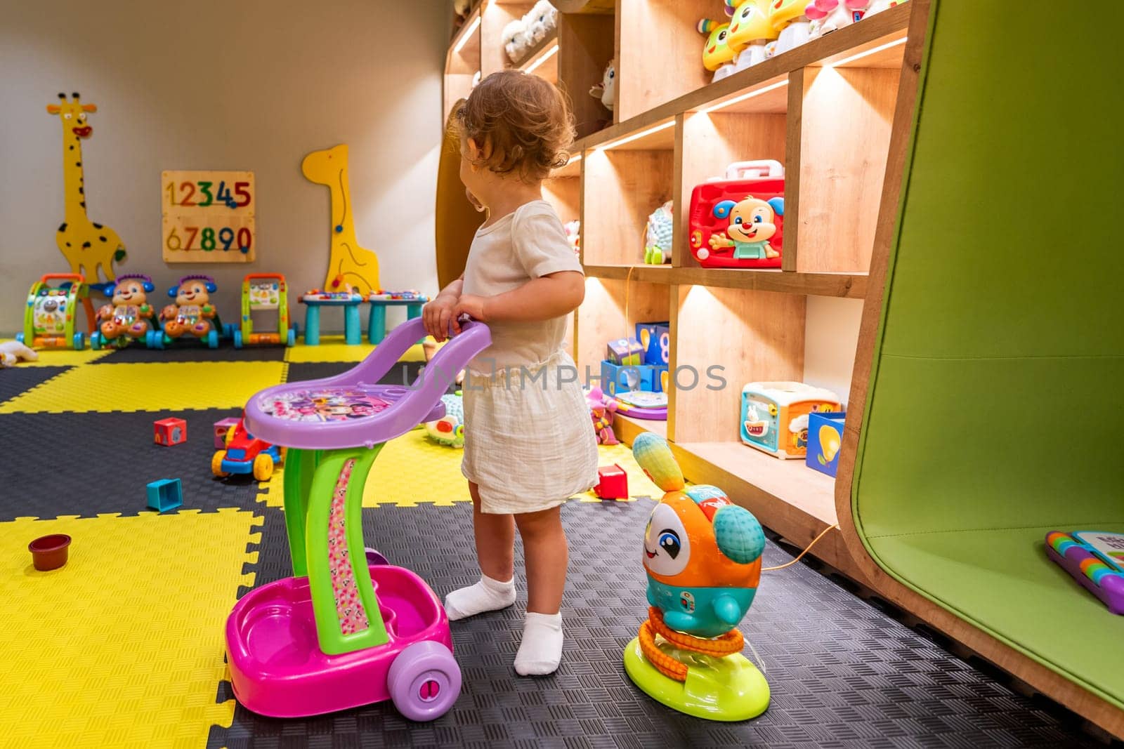 Child actively engaging with a toy cart in a vibrant playroom, surrounded by various educational toys and activities. Concept of fostering creativity and imagination in early childhood