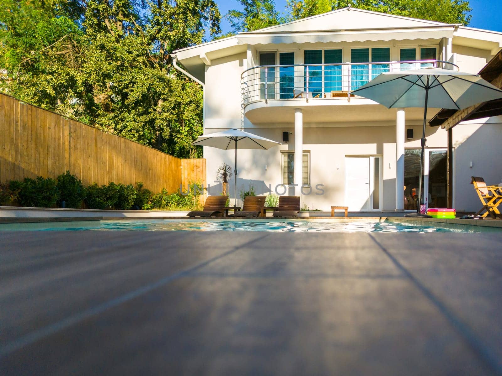 Modern residential house with swimming pool and patio. Luxury outdoor living space surrounded by greenery