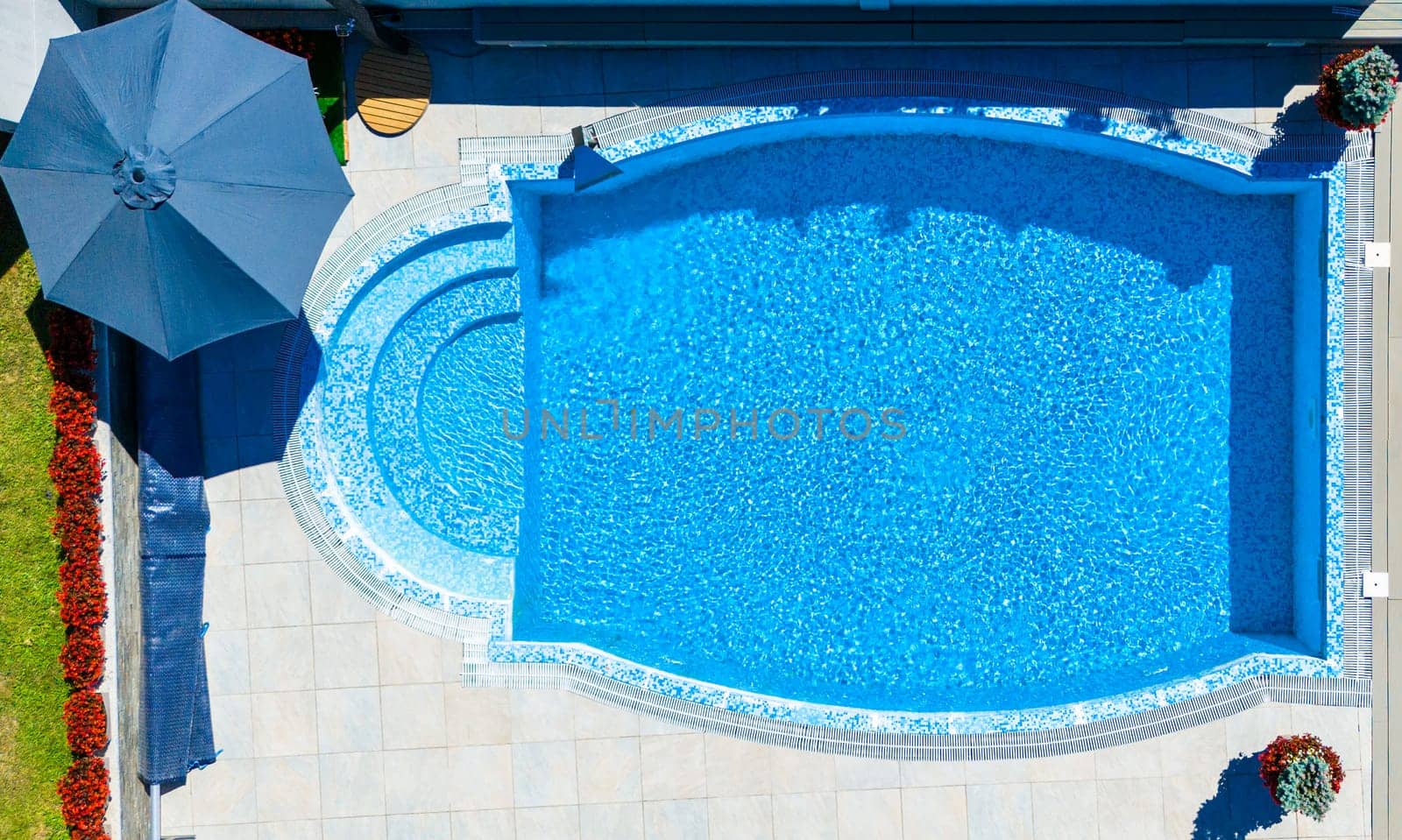 Top view of a luxurious oval pool with mosaic tiles and surrounding patio