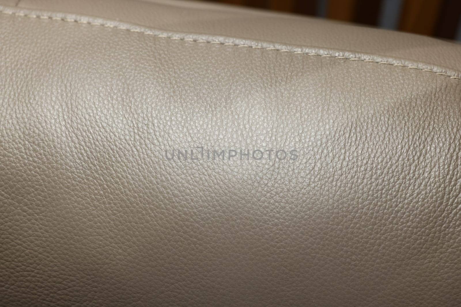 Closeup view of a smooth, luxurious beige leather surface, highlighting its unique texture and stitching