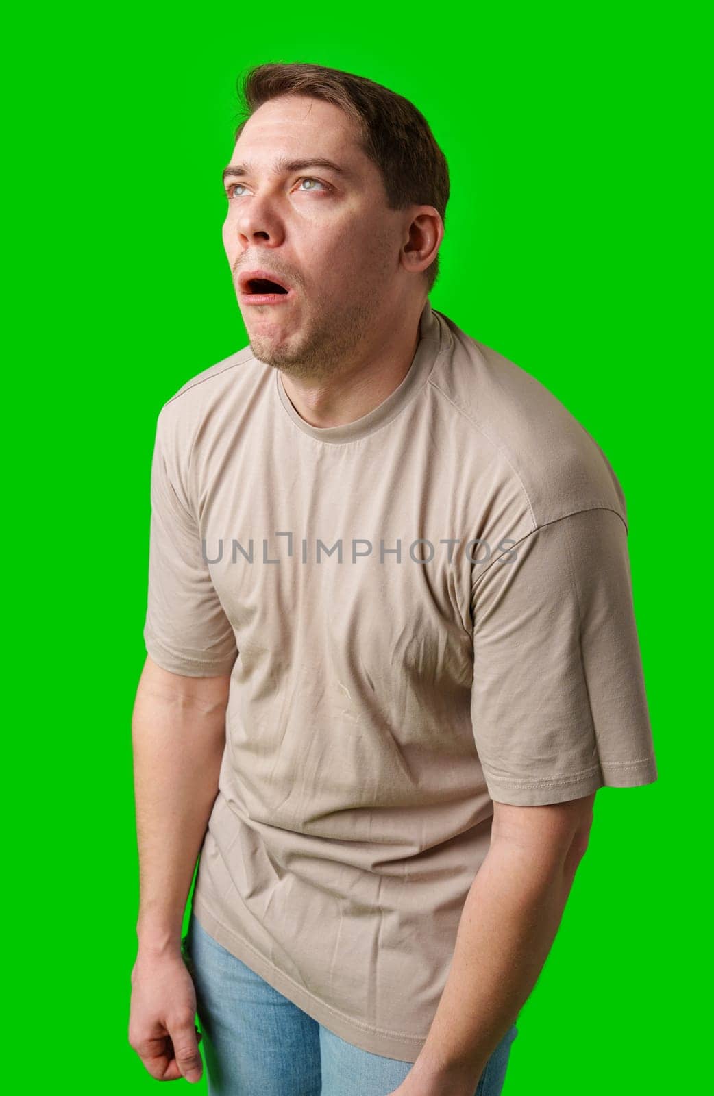 Man making a humorous expression against a bright green background in studio