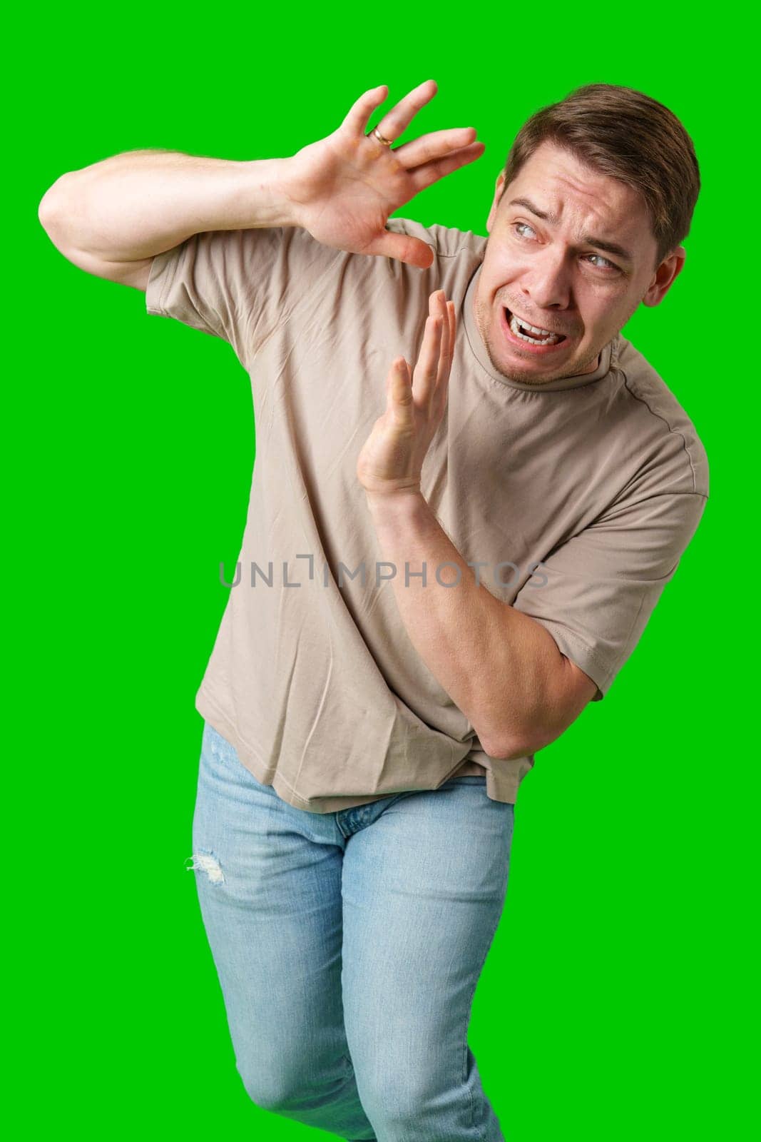 Man expressing fear while standing against a bright green background in studio