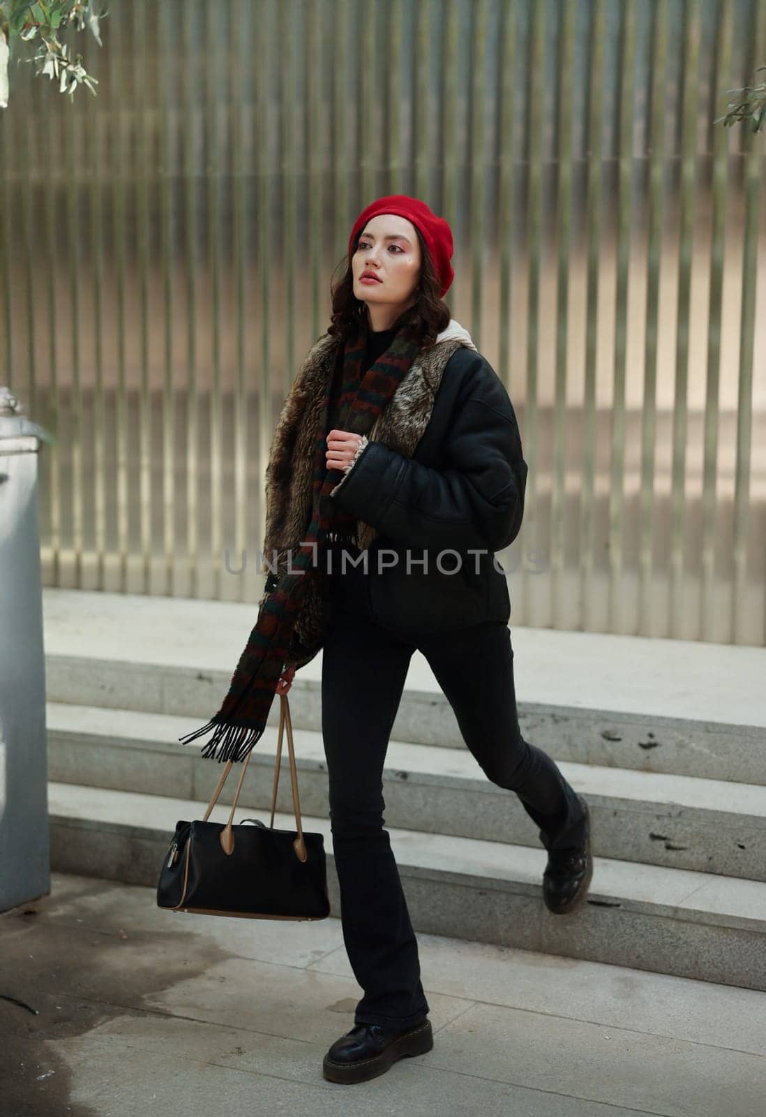 A young woman, dressed in trendy winter attire, walks confidently through a bustling urban environment