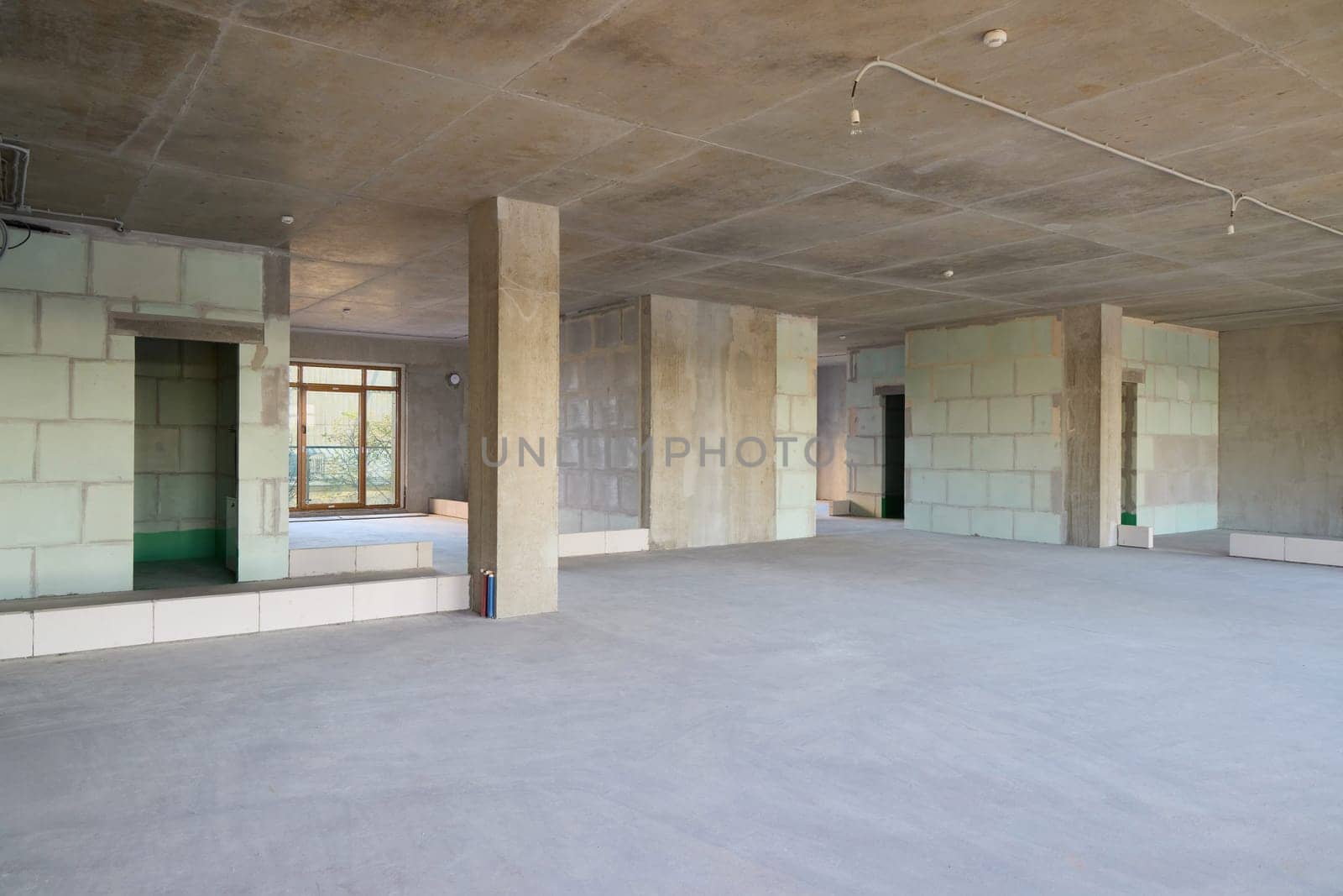 An expansive unfinished space featuring concrete walls and an open floor plan, ideal for renovation.