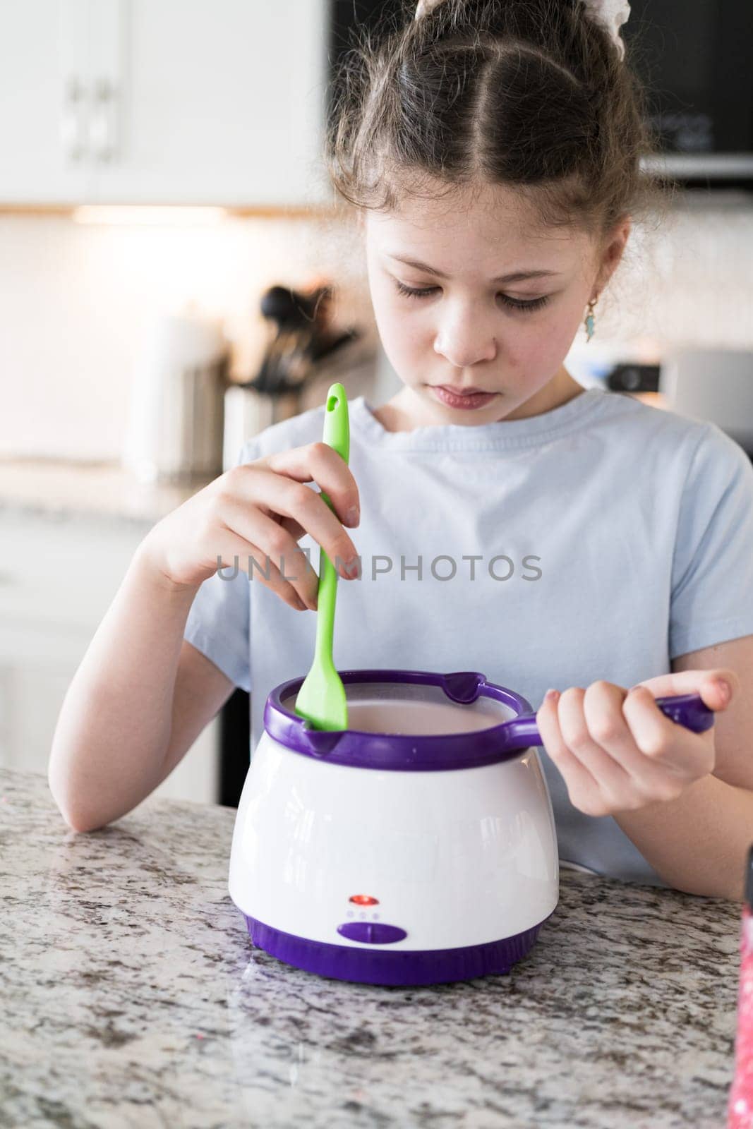 With focused attention, this budding culinary artist dips pretzels into a pot of melted chocolate, creating sweet delights in the warmth of a well-lit home kitchen.