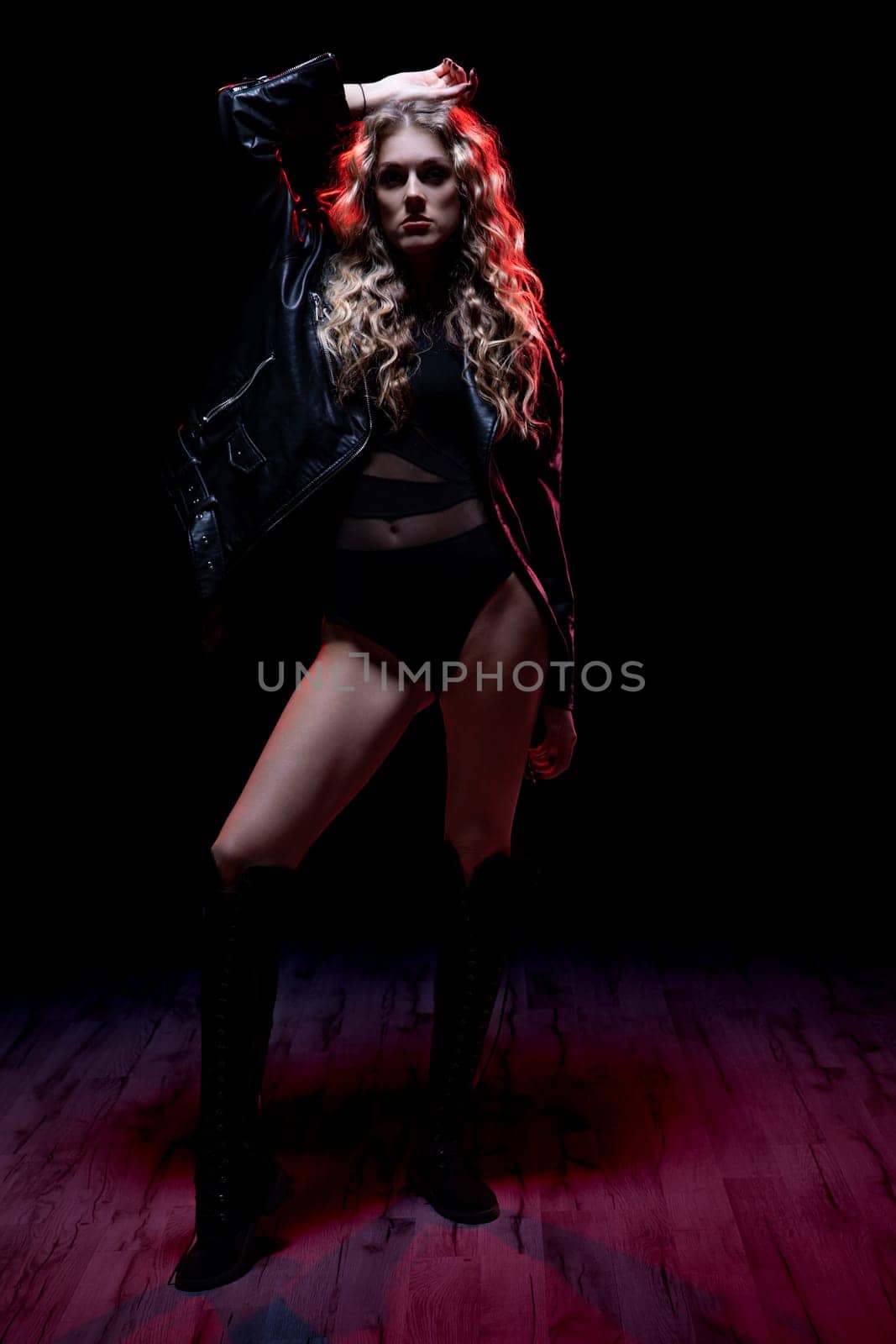 A striking fashion model poses confidently in dramatic lighting, showcasing modern style and attitude.