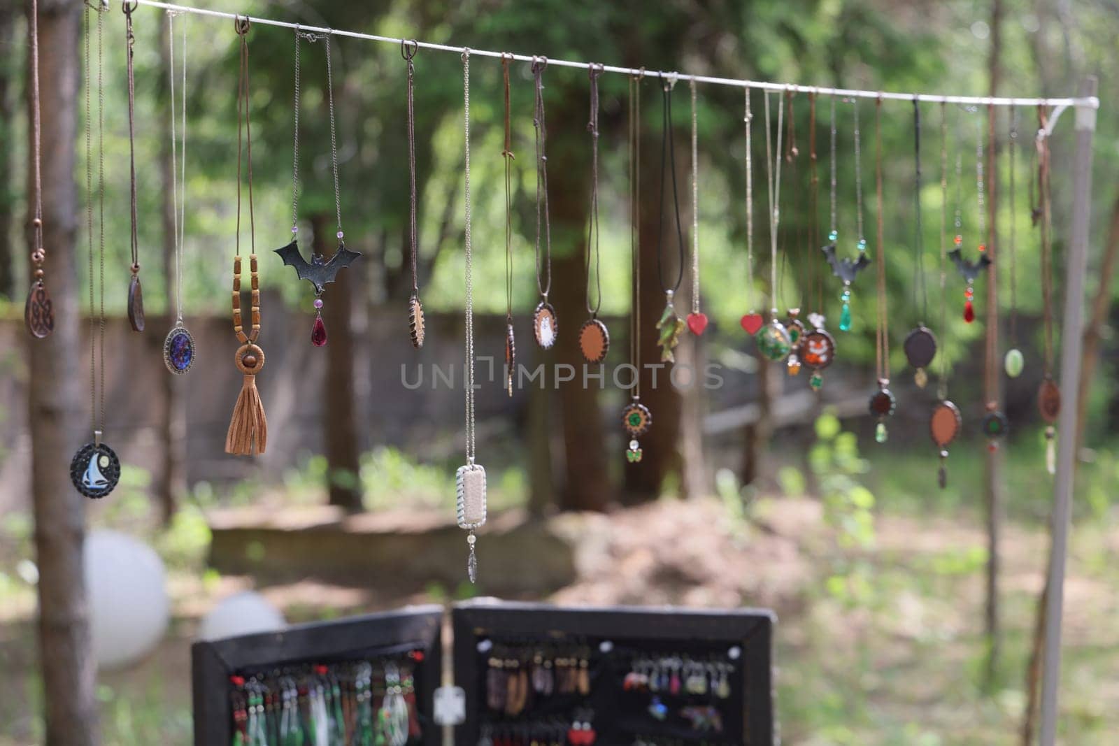 A vibrant and colorful display of unique jewelry pieces beautifully hanging in a serene outdoor setting