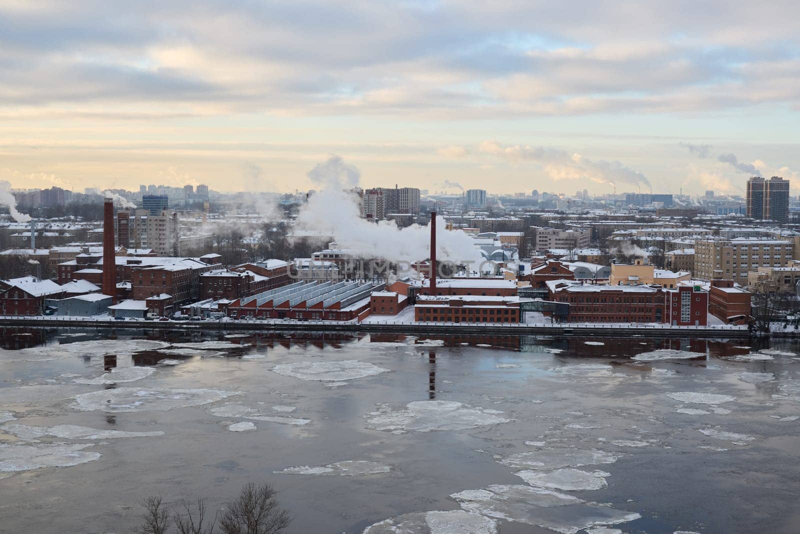 A breathtaking winter cityscape capturing the essence of industrial buildings located next to a frozen river