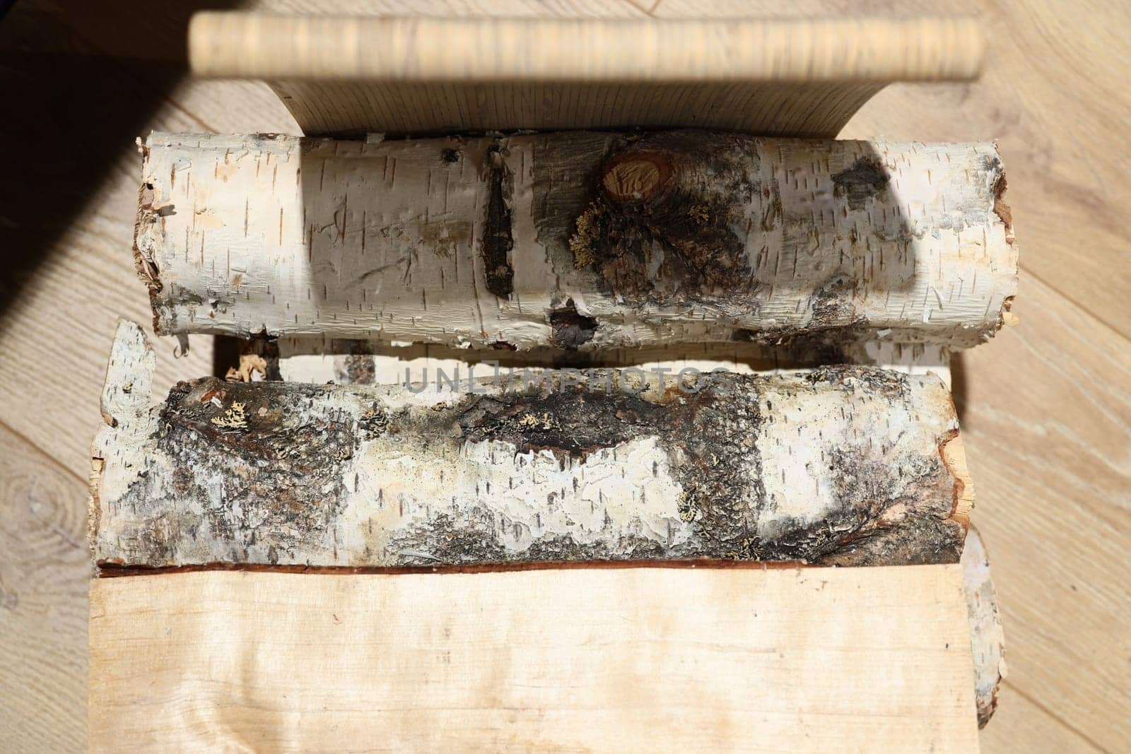 A closeup view of beautiful birch logs, complete with their bark, elegantly resting on a rustic wooden surface