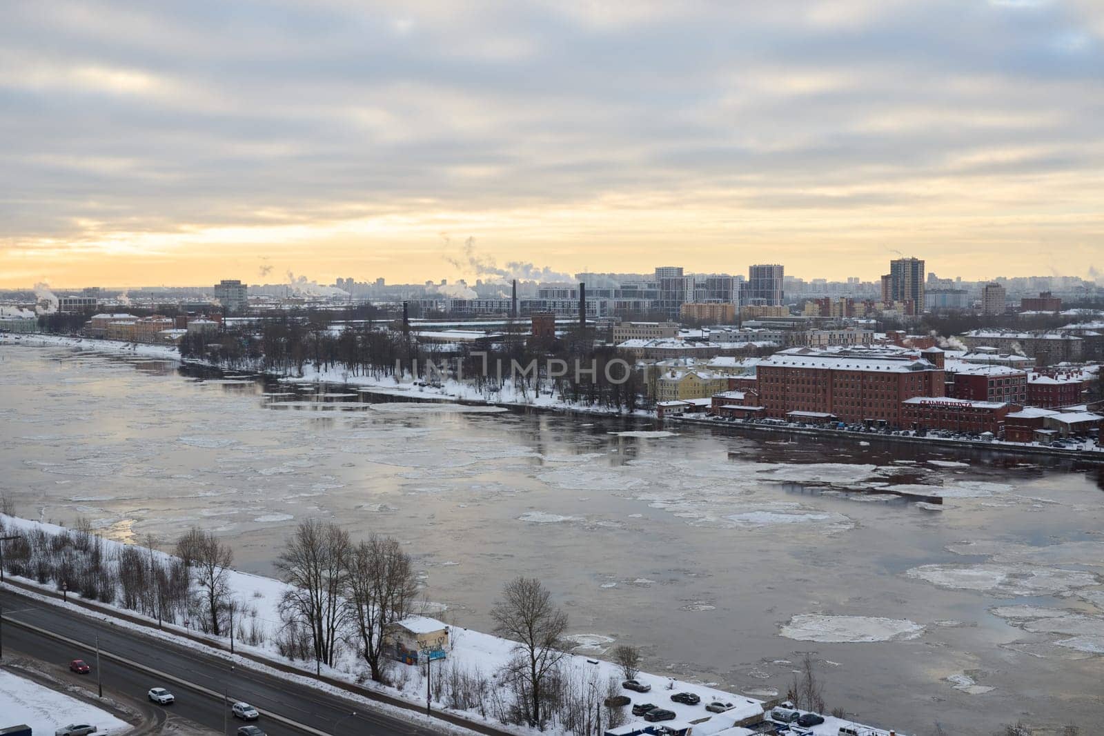 A tranquil winter scene beautifully showcasing a river encompassed by city buildings and stunning ice formations