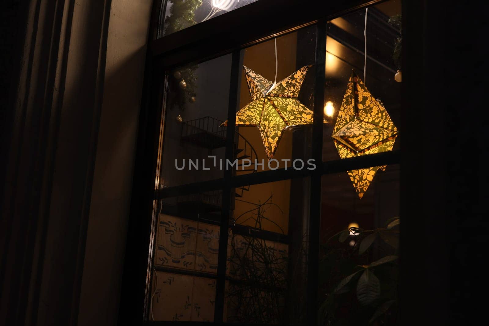 The starshaped lanterns emit a warm glow, adorning a window and enhancing the cozy nighttime ambiance