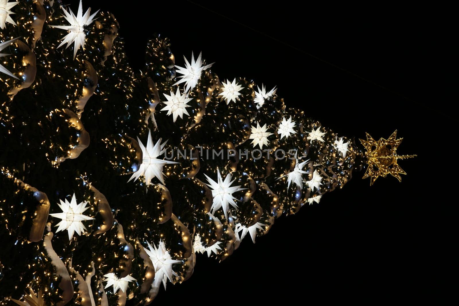 A stunning Christmas tree adorned with twinkling lights and shining stars in a dark, enchanting setting