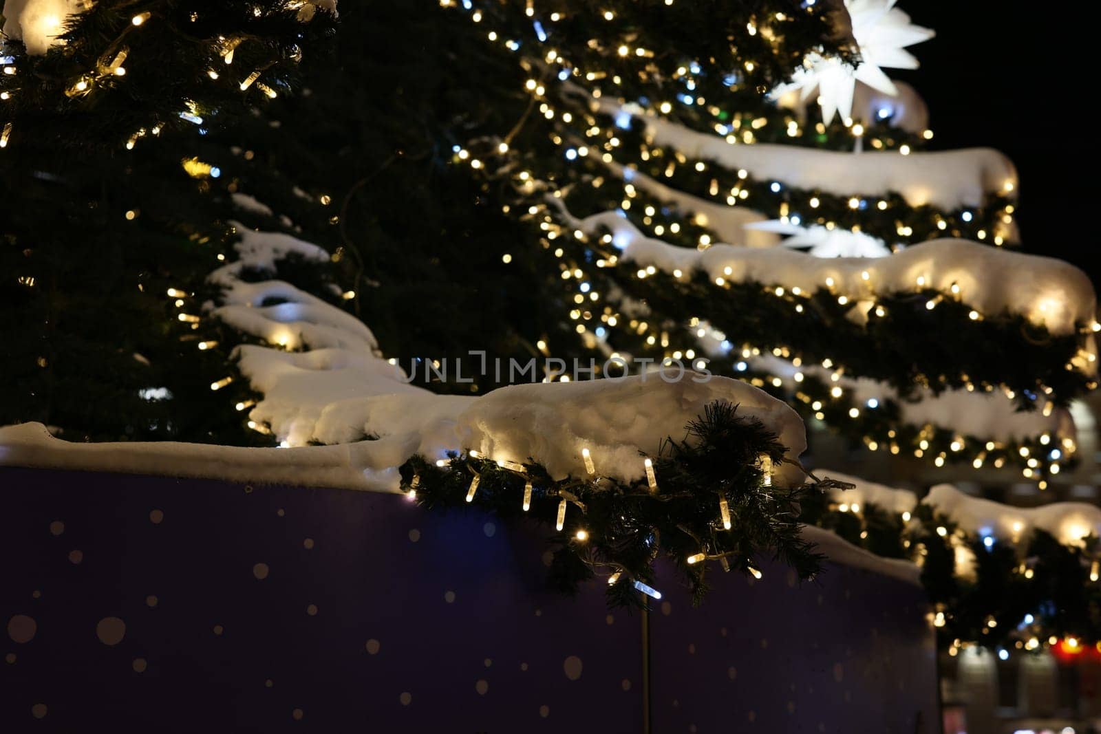 A beautifully lit Christmas tree adorned with snow, showcasing stunning festive decorations for the holiday season