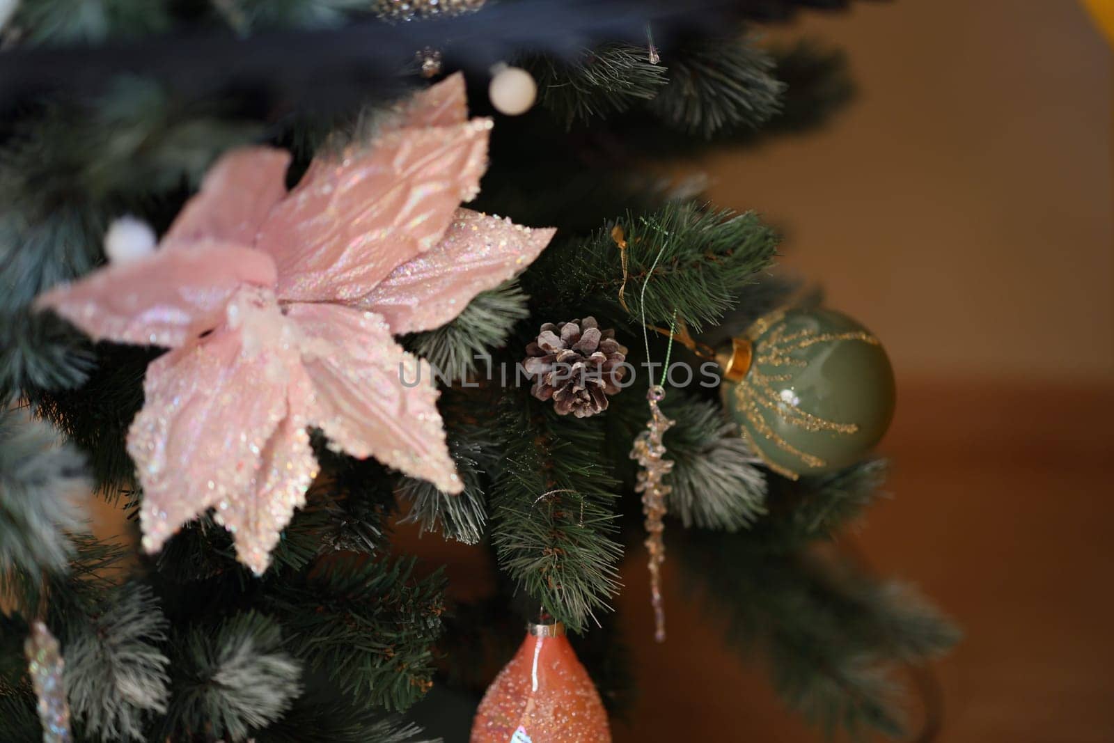 A beautifully adorned Christmas tree that showcases vibrant pink flowers alongside various festive ornaments