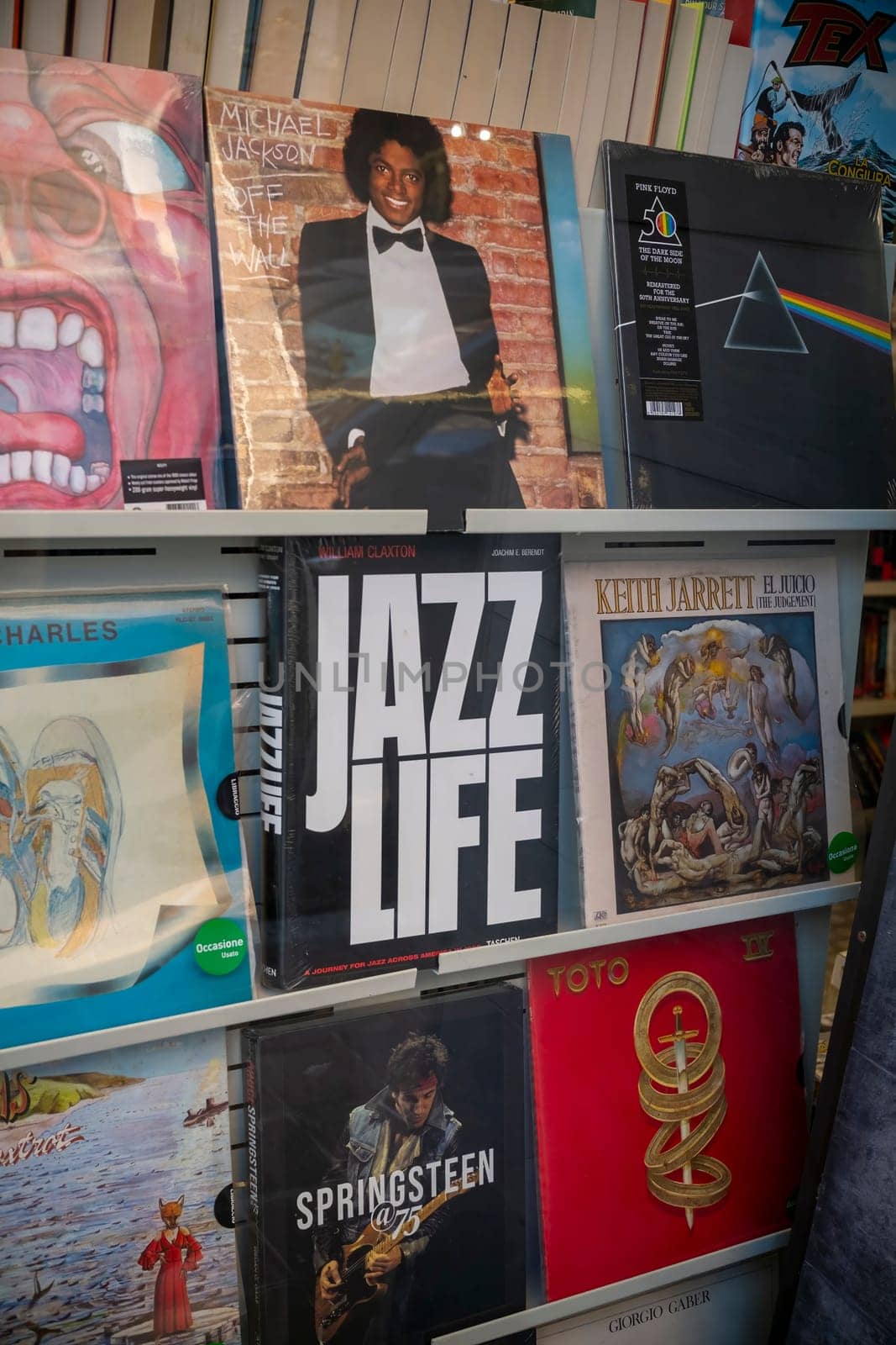 Cremona, Italy - November 27th 2024 Vinyl records showcasing iconic artists like michael jackson, pink floyd, and bruce springsteen are displayed on a rack in a bookstore in cremona, italy
