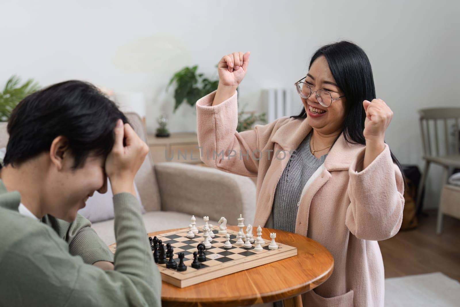 A happy mother and son enjoy playing board games together, fostering family bonding and fun in a warm, inviting home environment.