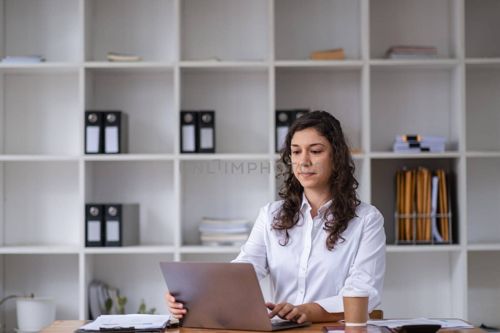 Professional businesswoman focused on work at her desk in a contemporary office setting.