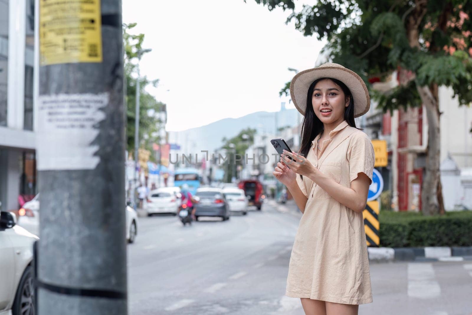 A young woman walks through the city, capturing the essence of modern urban life with her smartphone in hand.