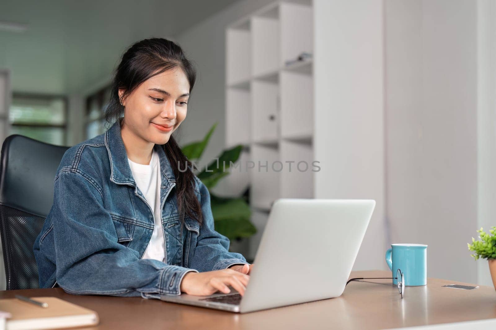 A young woman studying online at home, using a laptop, and staying focused and engaged in her remote education.
