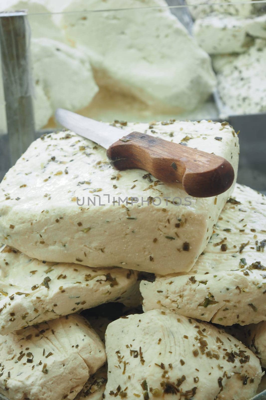Several blocks of delicious herbal cheese artfully arranged with a wooden knife placed on top
