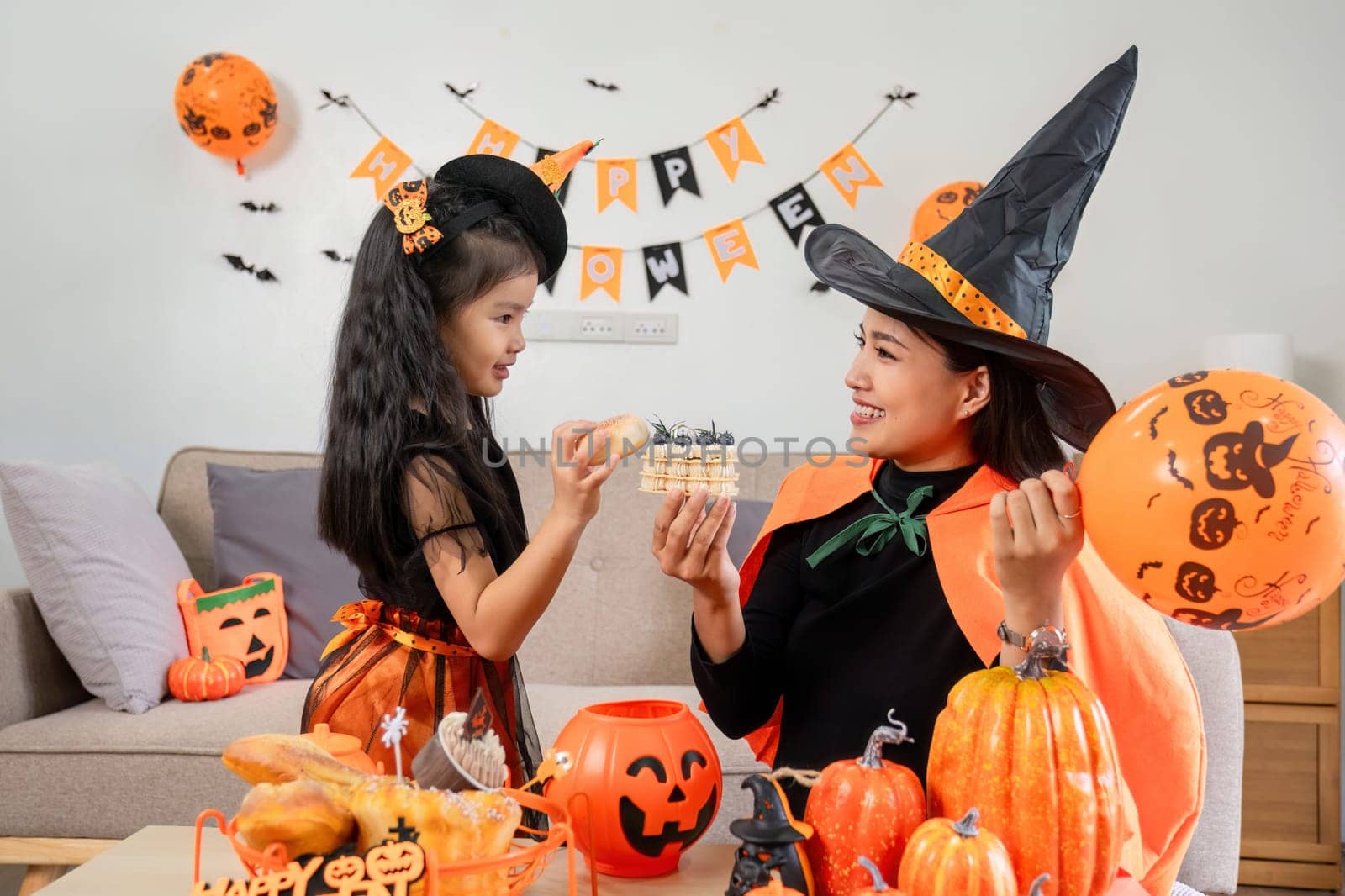 A mother and child dressed in Halloween costumes engage in fun activities together, surrounded by festive decorations and treats.