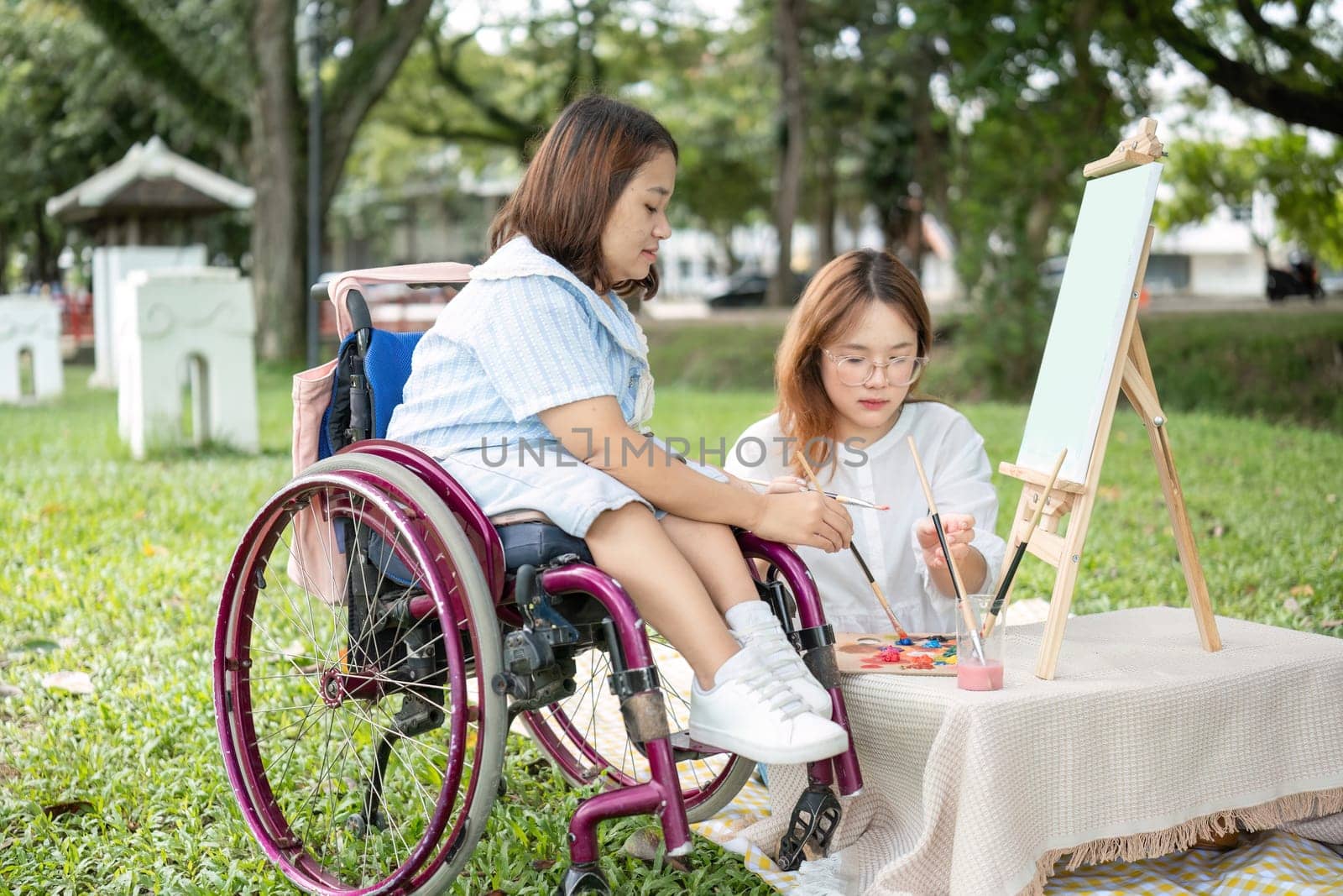 Two close friends, one in a wheelchair, drawing together outdoors in a park, showcasing creativity, inclusion, and friendship.