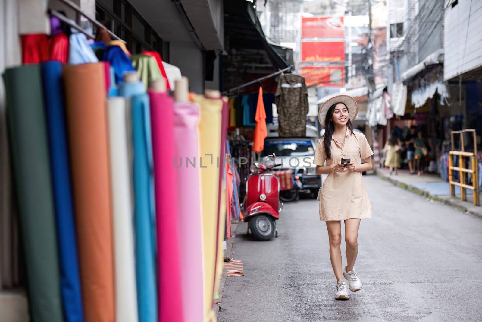 A young woman walks confidently through the city, showcasing a modern urban lifestyle with her smartphone and trendy outfit.