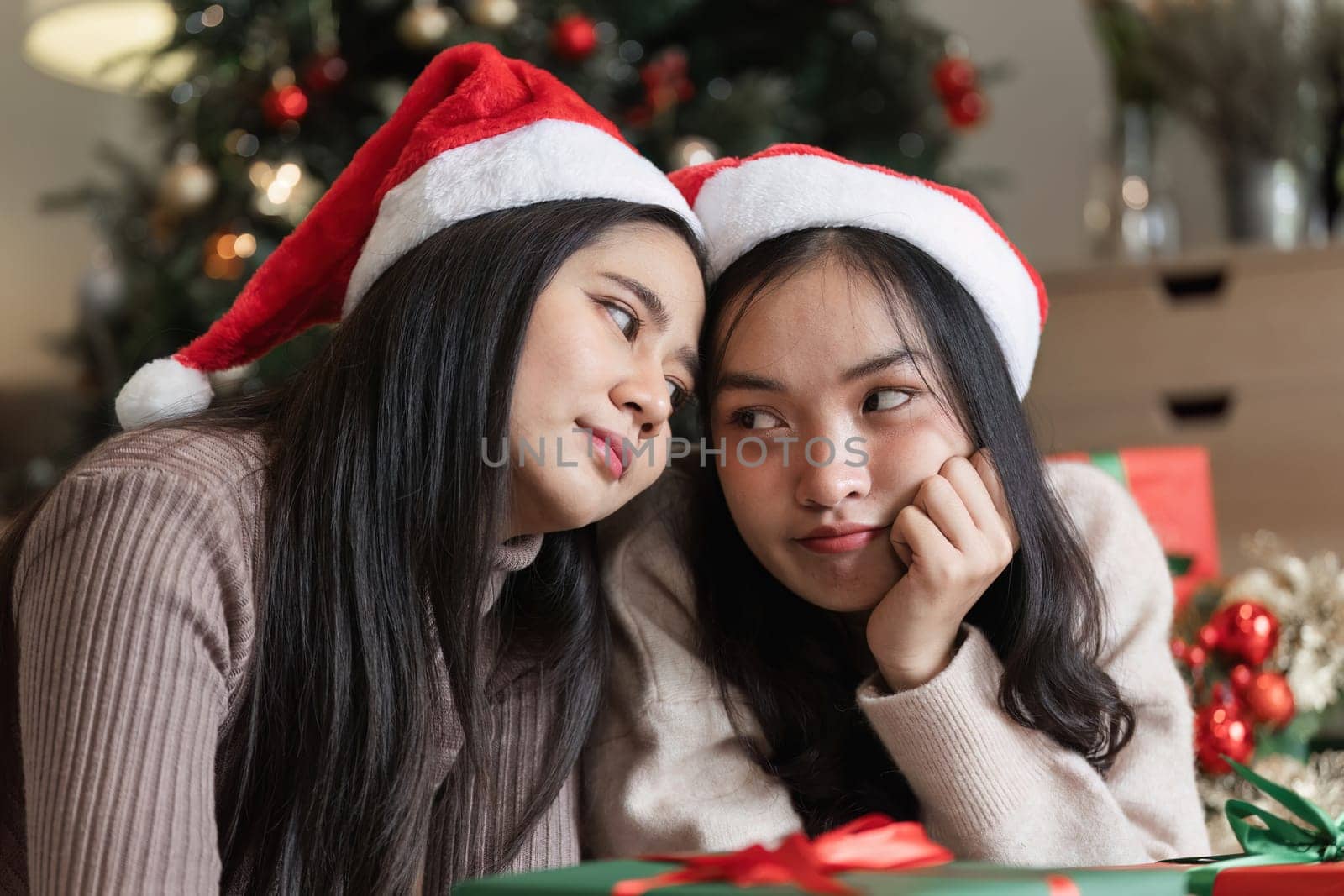 Happy young female couple enjoying Christmas Eve, surrounded by festive decorations and a warm, joyful atmosphere.