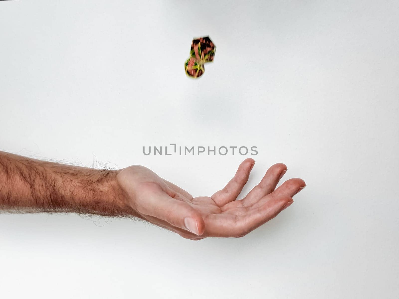 Hand tossing colorful dice against white background capturing motion.