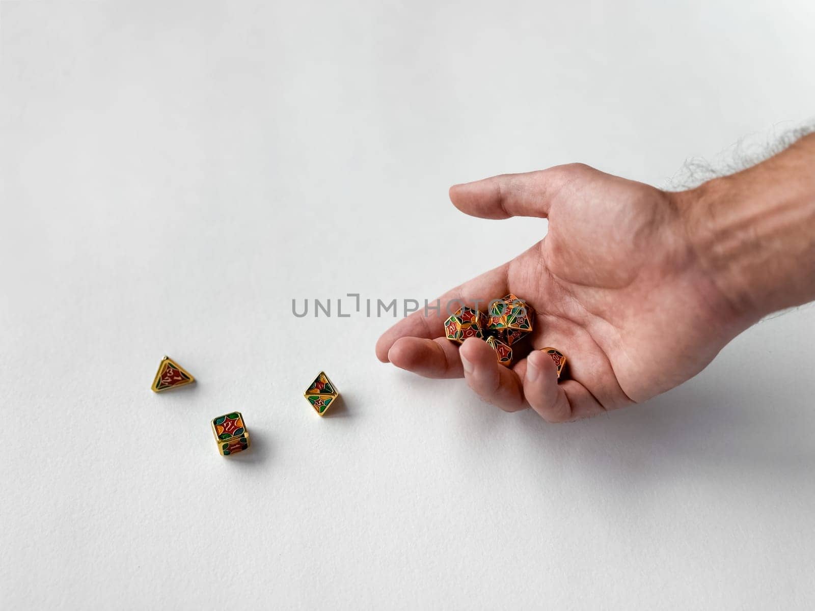 Hand holding colorful polyhedral dice on white surface for tabletop gaming.