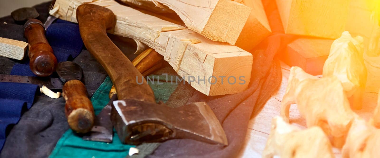 A small group of carved wooden animals stands on a workbench, emerging from the chaos of a woodworker's workshop. A large axe and various tools are scattered across the surface, hinting at the intricate process that brought the animal figures to life. A piece of unfinished wood is still being worked on, suggesting that more creations are yet to be born.