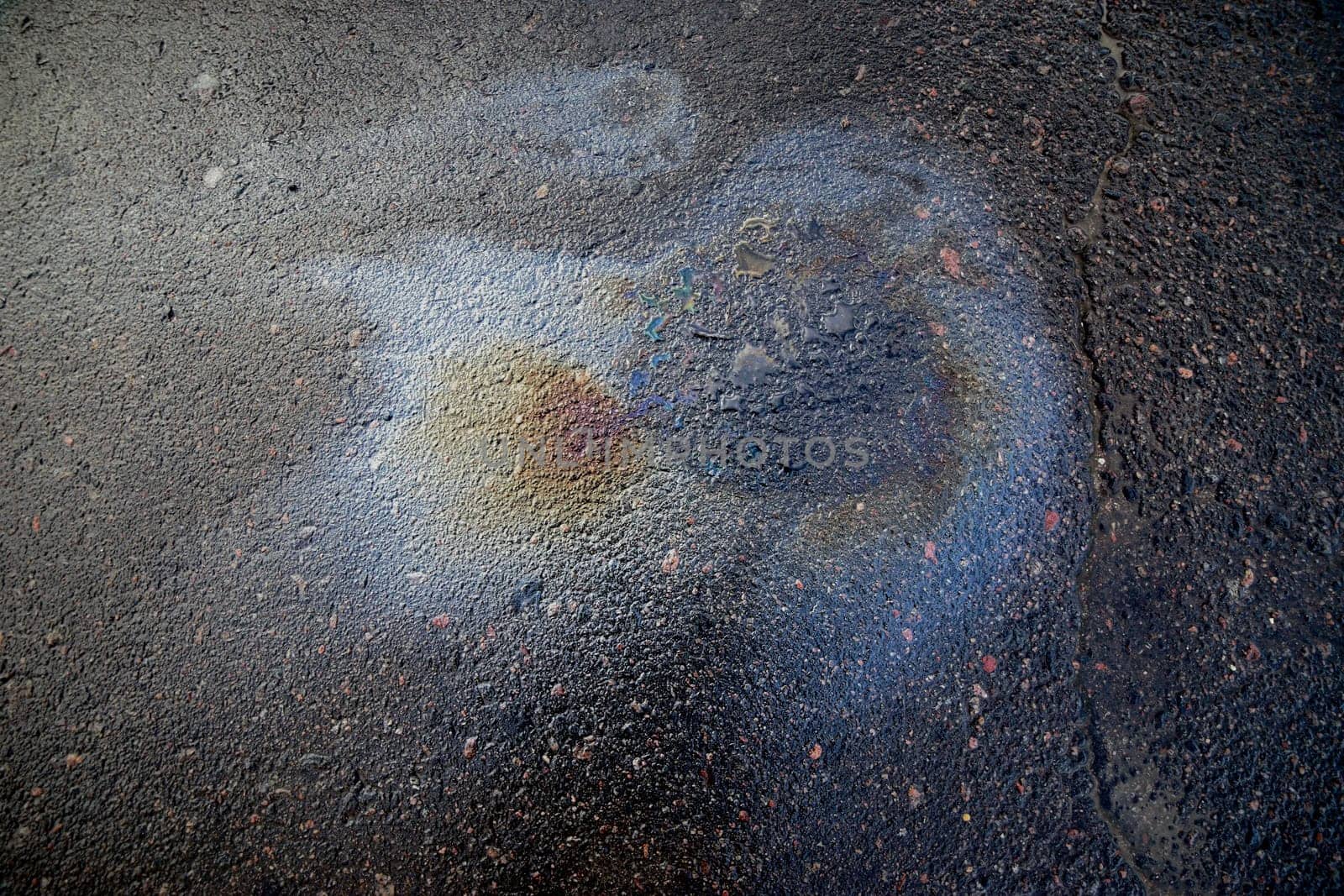 A bright petrol or oil slick creating a colourful sheen on a black asphalt road.