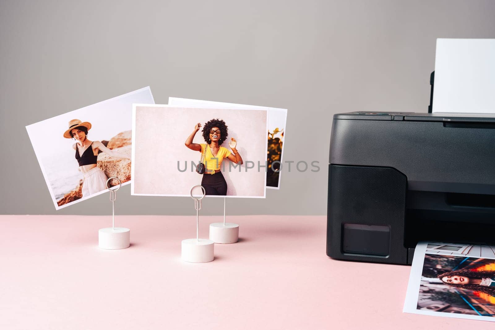 Modern laser printer printing color photos of women close up on desk