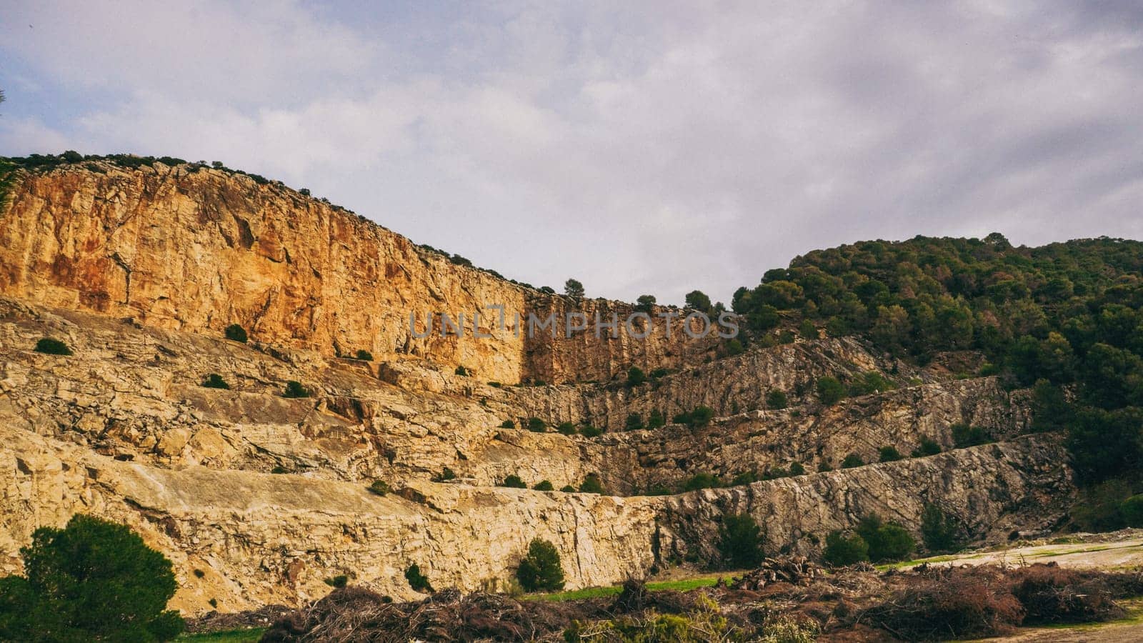 Majestic cliffs rise prominently against a cloudy sky, showcasing the remarkable beauty and textures of nature