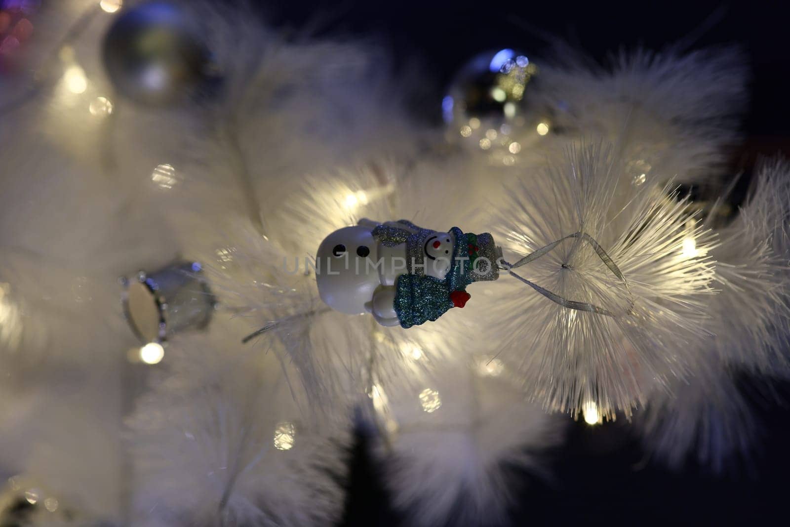A delightful and charming snowman ornament is hanging beautifully on a whimsical white Christmas tree, adding cheer