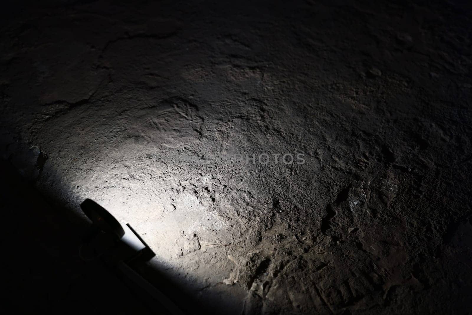 A bright beam of light shines on a richly textured dark surface, enhancing the contrast and adding depth