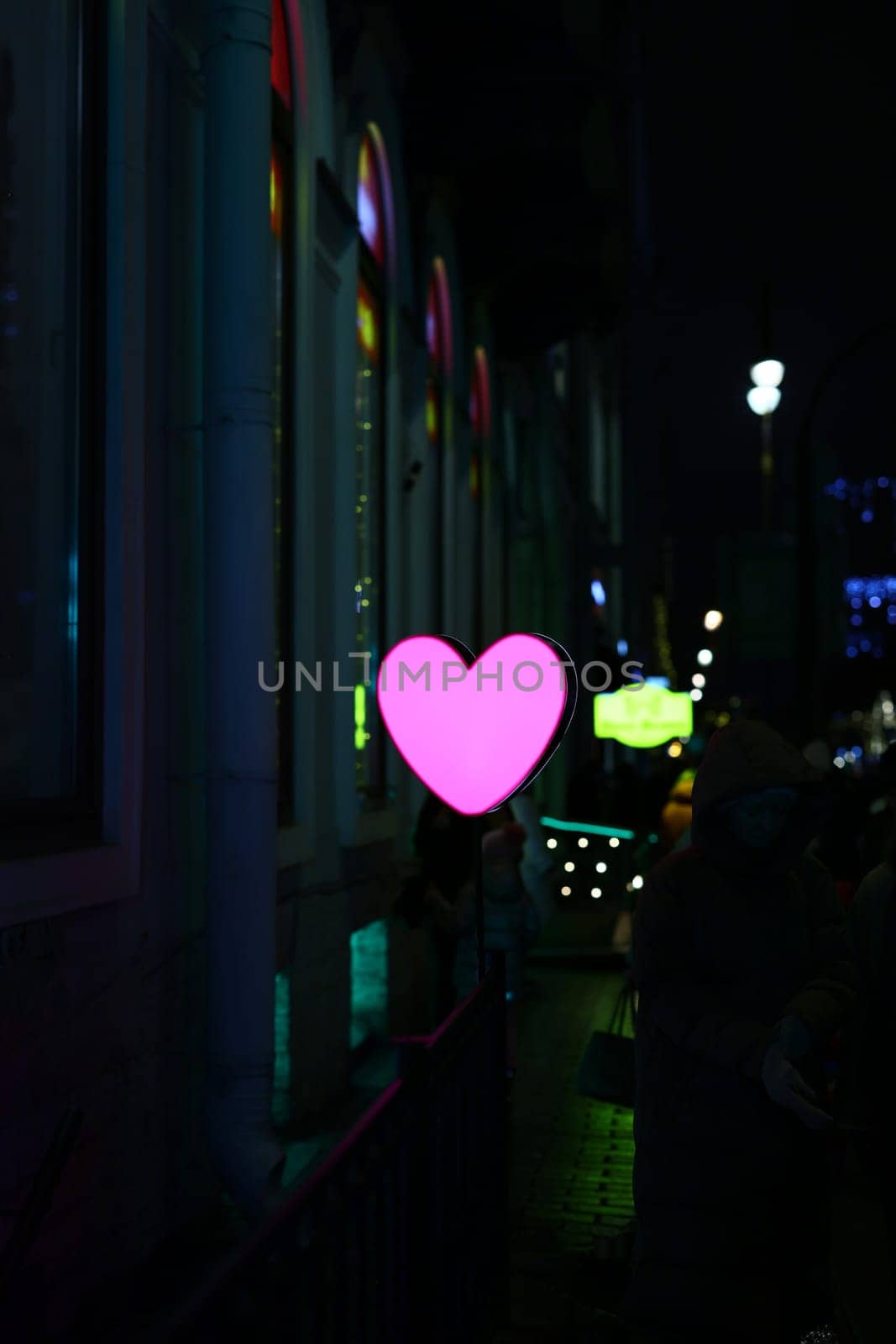 A pink heart light shines brightly against a colorful night backdrop, ideal for romantic themes and mood