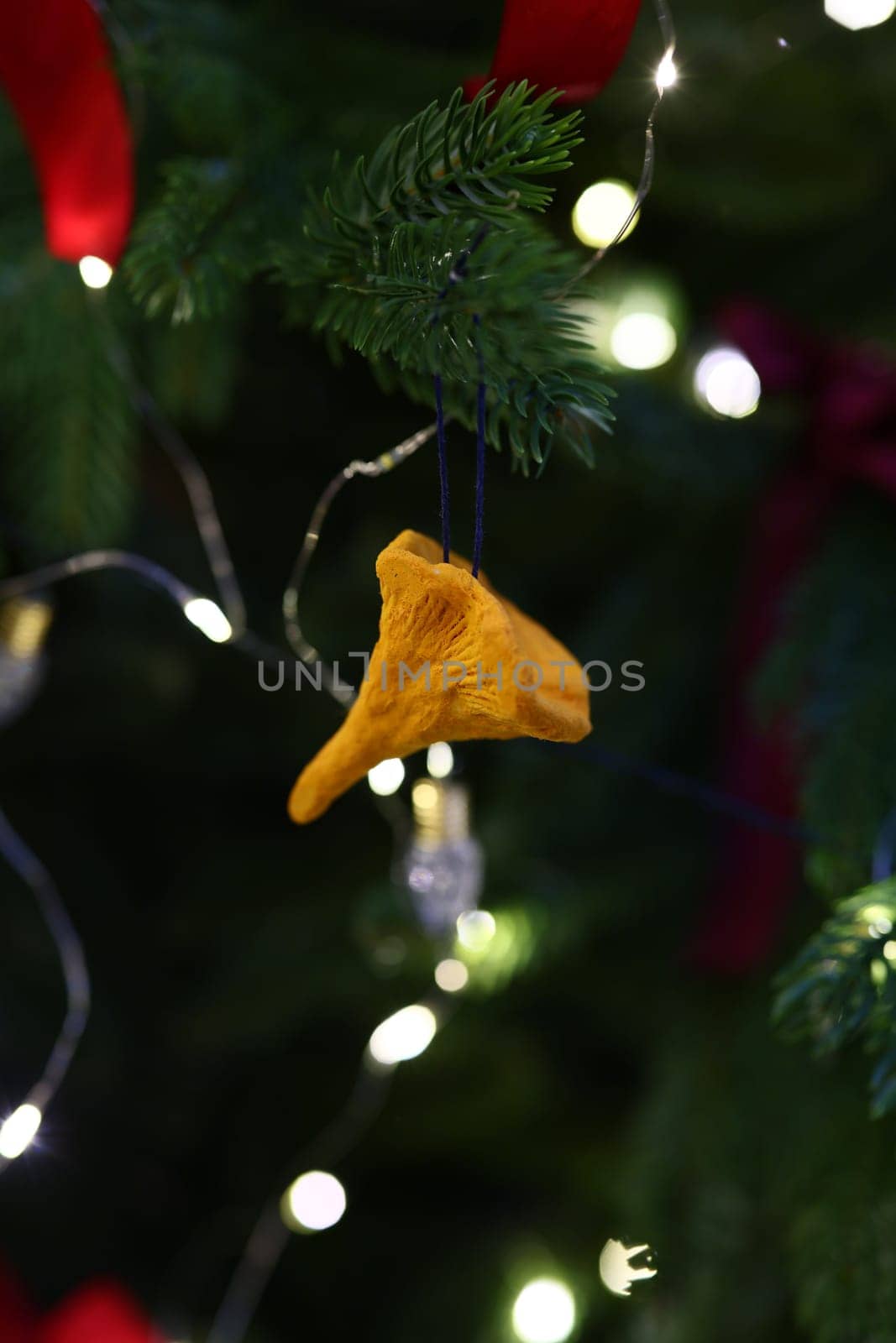 A vibrant yellow ornament perfectly hanging amidst colorful festive lights beautifully adorning a Christmas tree