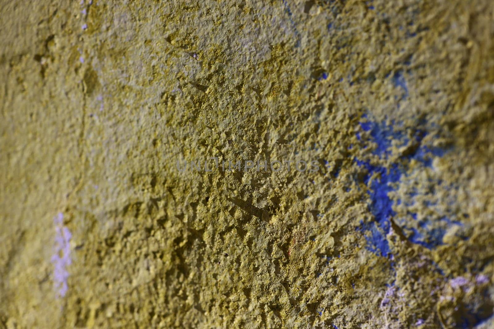 This is a closeup of a beautifully textured yellow wall that features subtle blue accents with rough details