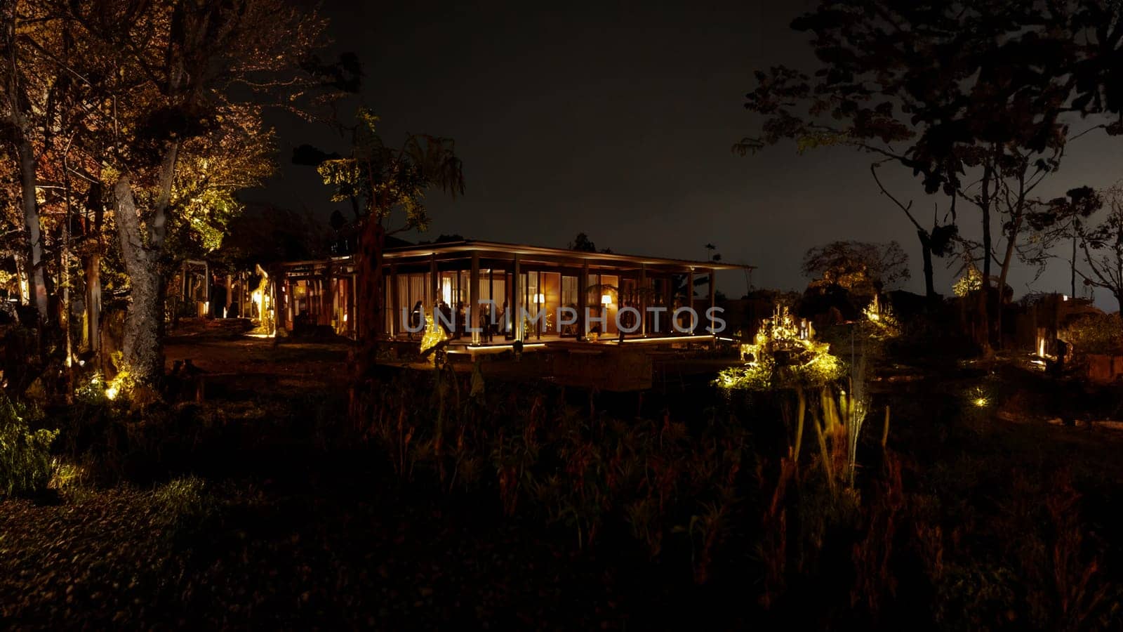 Secluded cabin illuminated at night amidst forest trees, offering a tranquil and cozy retreat in nature.