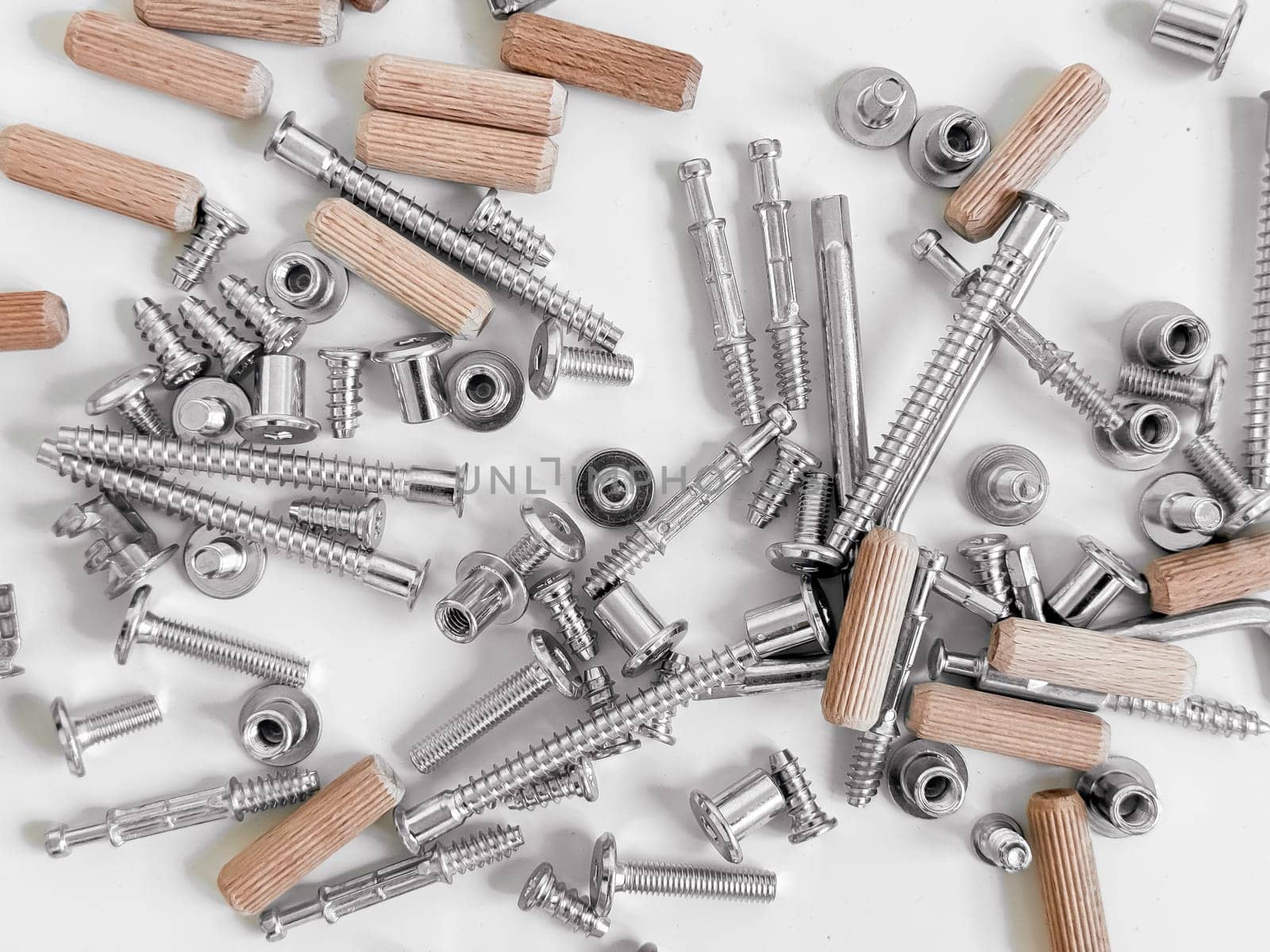 Assorted hardware pieces. Screws, dowels, and fasteners on white background.