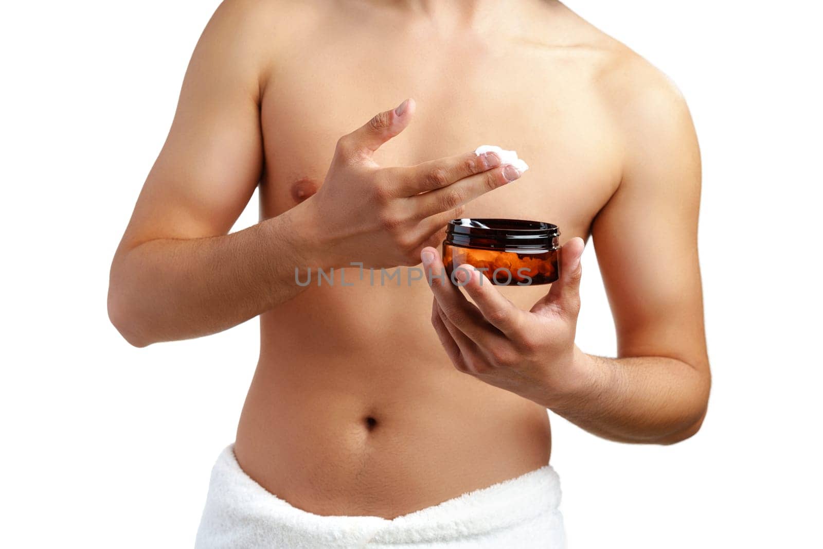 A young man applying skincare cream on his face with a focused expression, demonstrating personal grooming at home close up