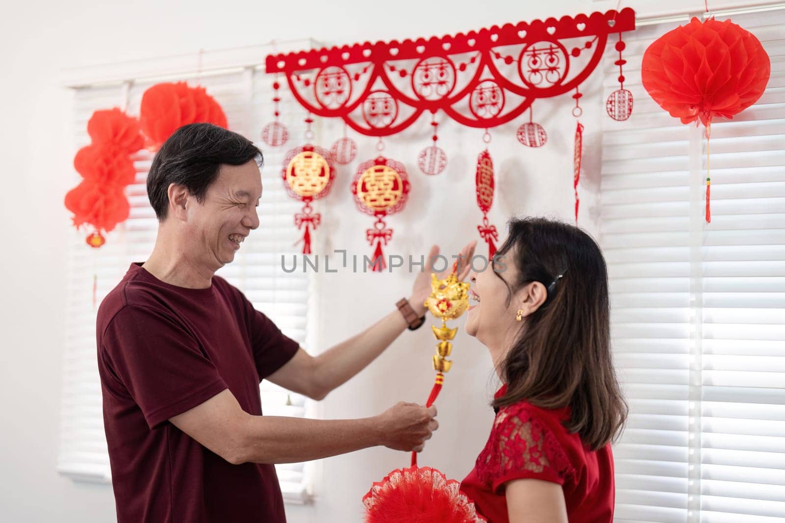 A joyful elderly couple enjoys the festivities of Chinese New Year surrounded by vibrant decorations and happy moments.