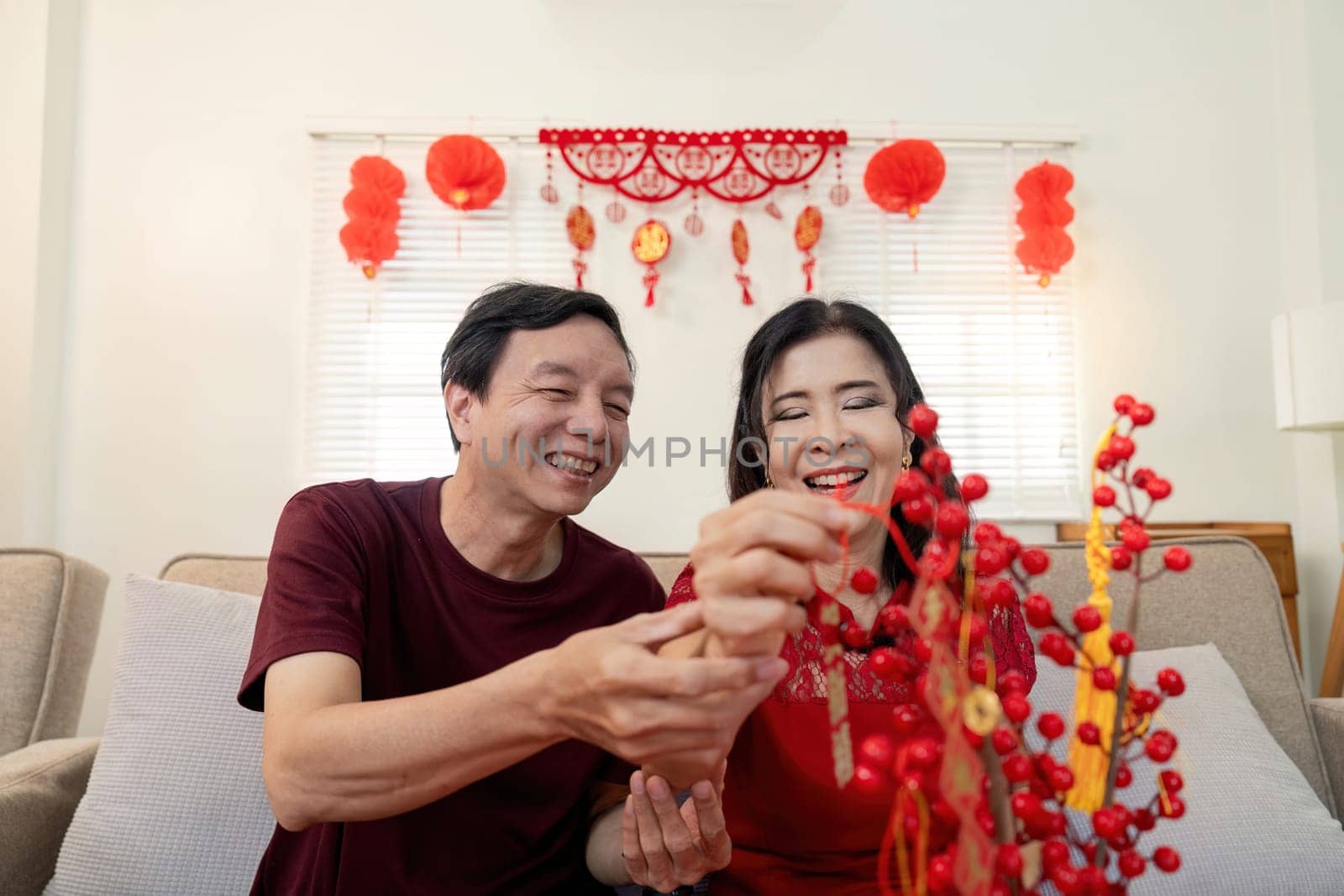 An elderly couple enjoys the festive spirit of Chinese New Year sharing laughter and decorating together.