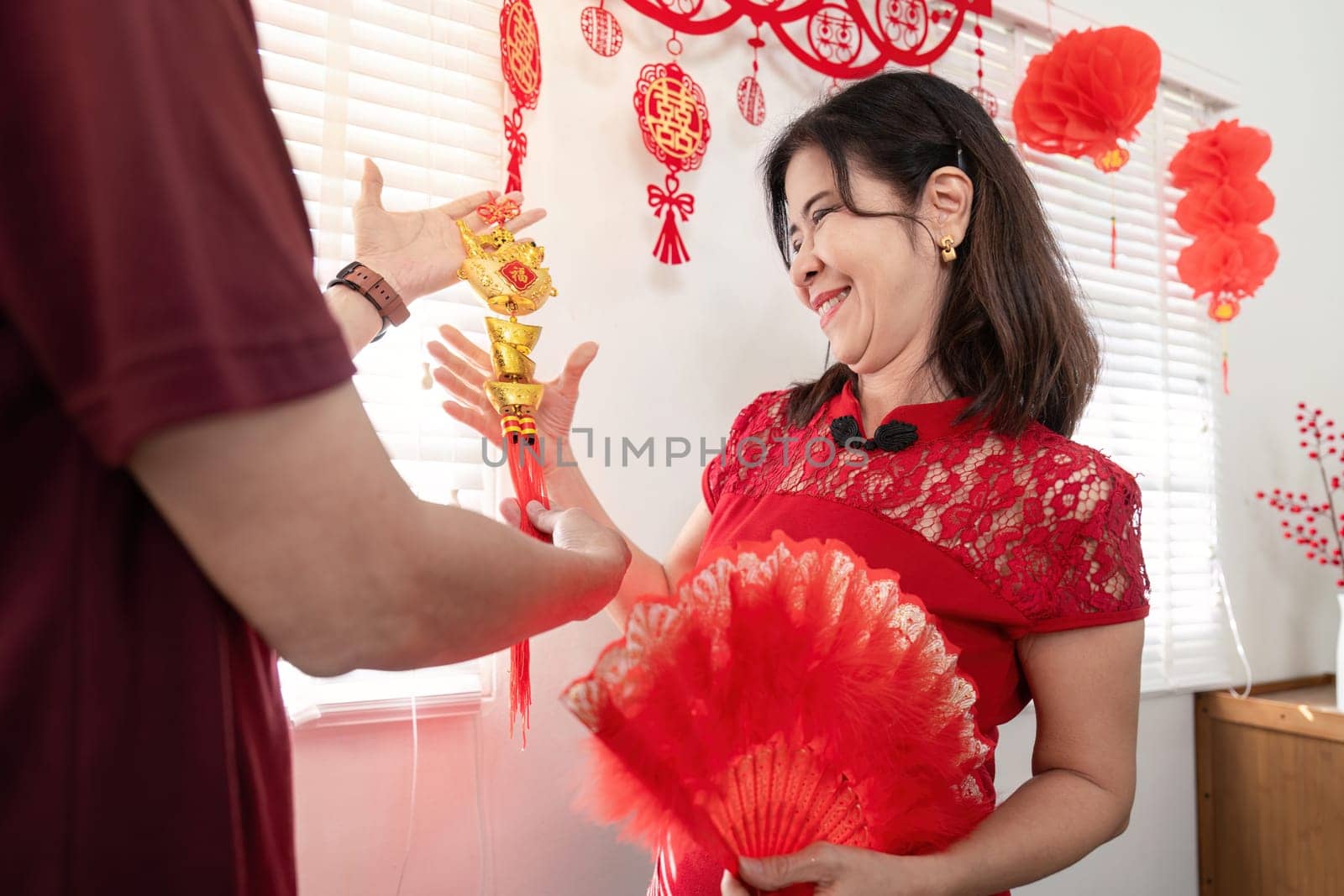 An elderly couple joyfully celebrates Chinese New Year at home surrounded by vibrant decorations and festive spirit.