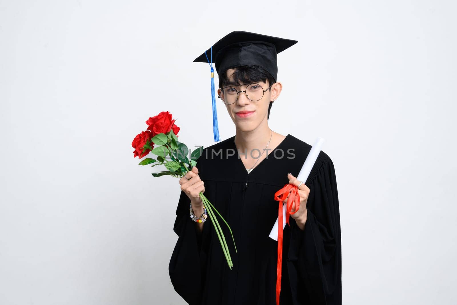 Proud graduate holding a bouquet and diploma standing on white background. Academic achievement concept.