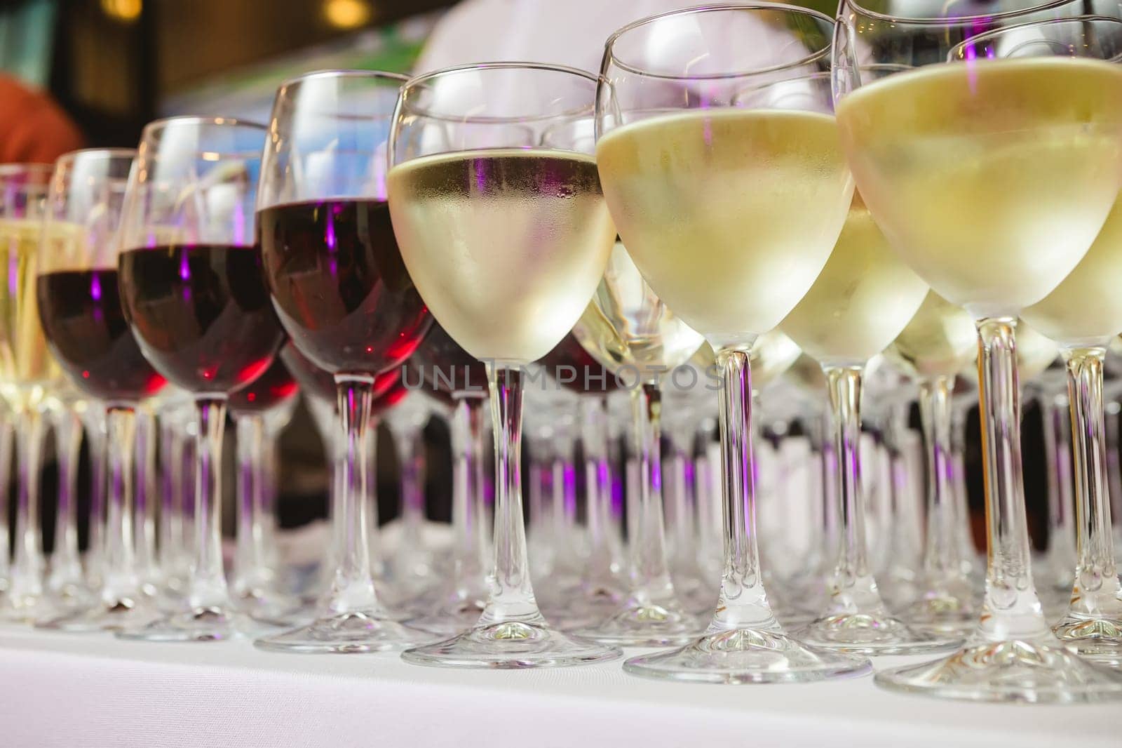 A beautifully arranged collection of wine glasses filled with red and white wines, set on a white tablecloth. The image captures an elegant scene perfect for events such as parties, weddings, or wine tastings
