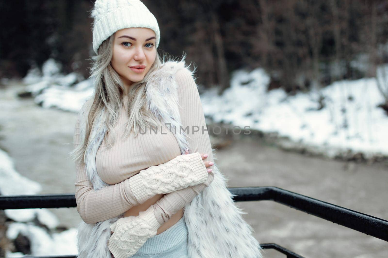 Portrait of a sexy girl in a fur vest and a fluffy hat in the winter season. Beautiful sexy breasts visible through t-shirt.