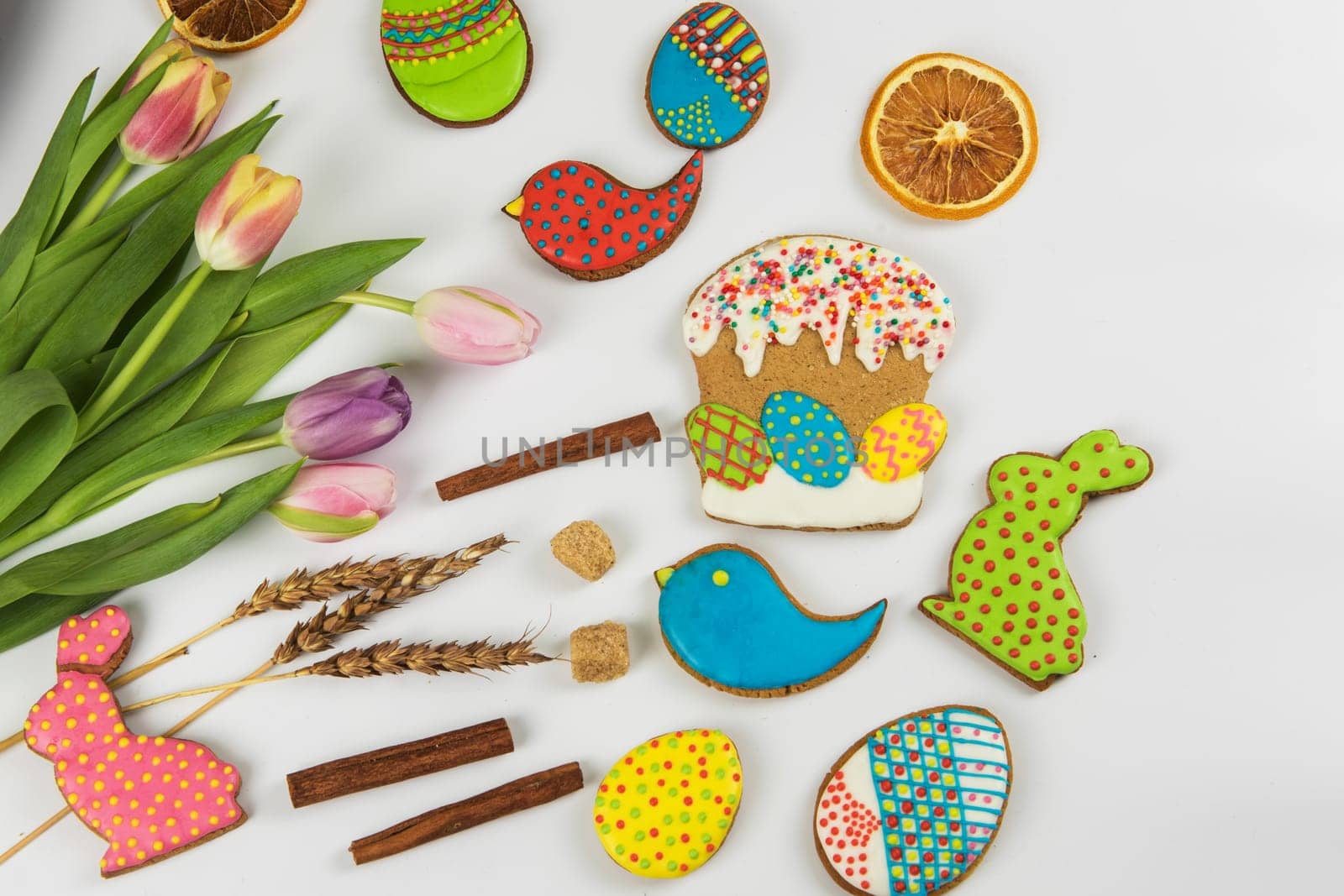 Tulips and gingerbread cookies on white background for Easter.