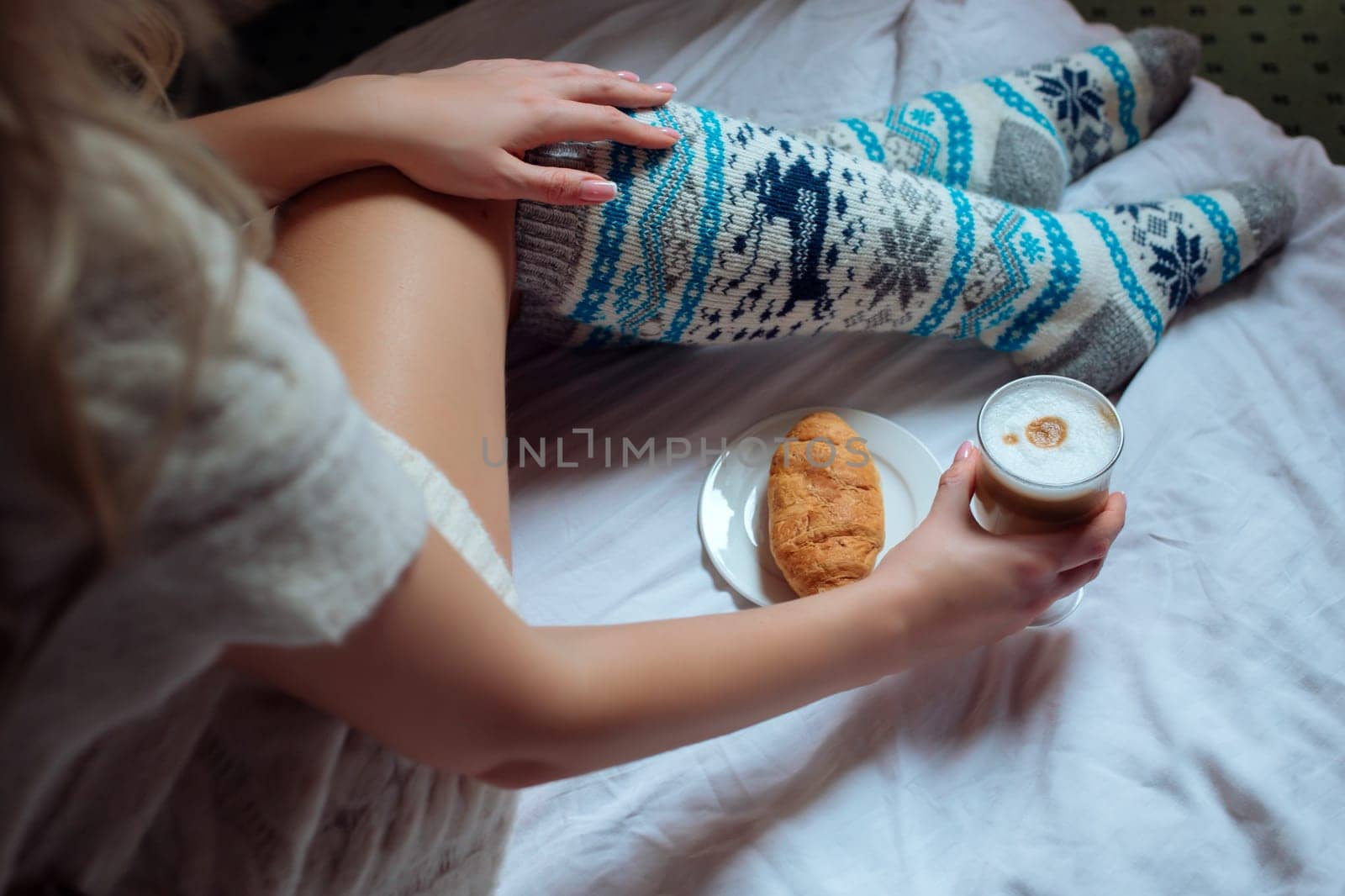 A young beautiful woman in warm handmade knitted clothes at home. . spring, winter season. Gaiters. Knee socks. Leggings.